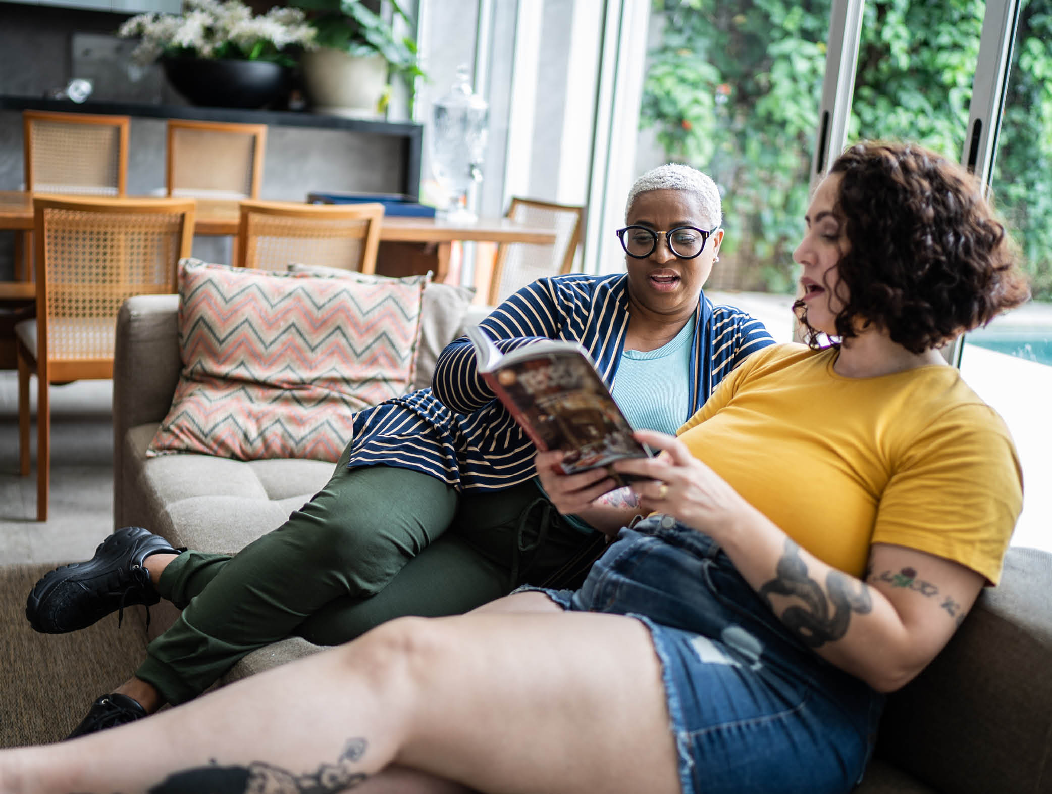 Mid adult woman talking with a friend and reading a book at home