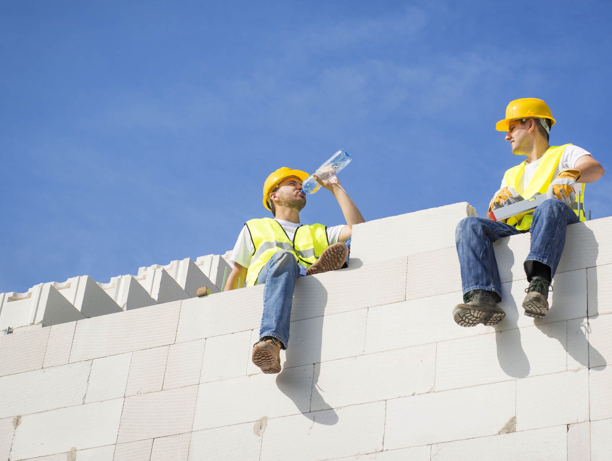 Builders are working on the top of house construction.
