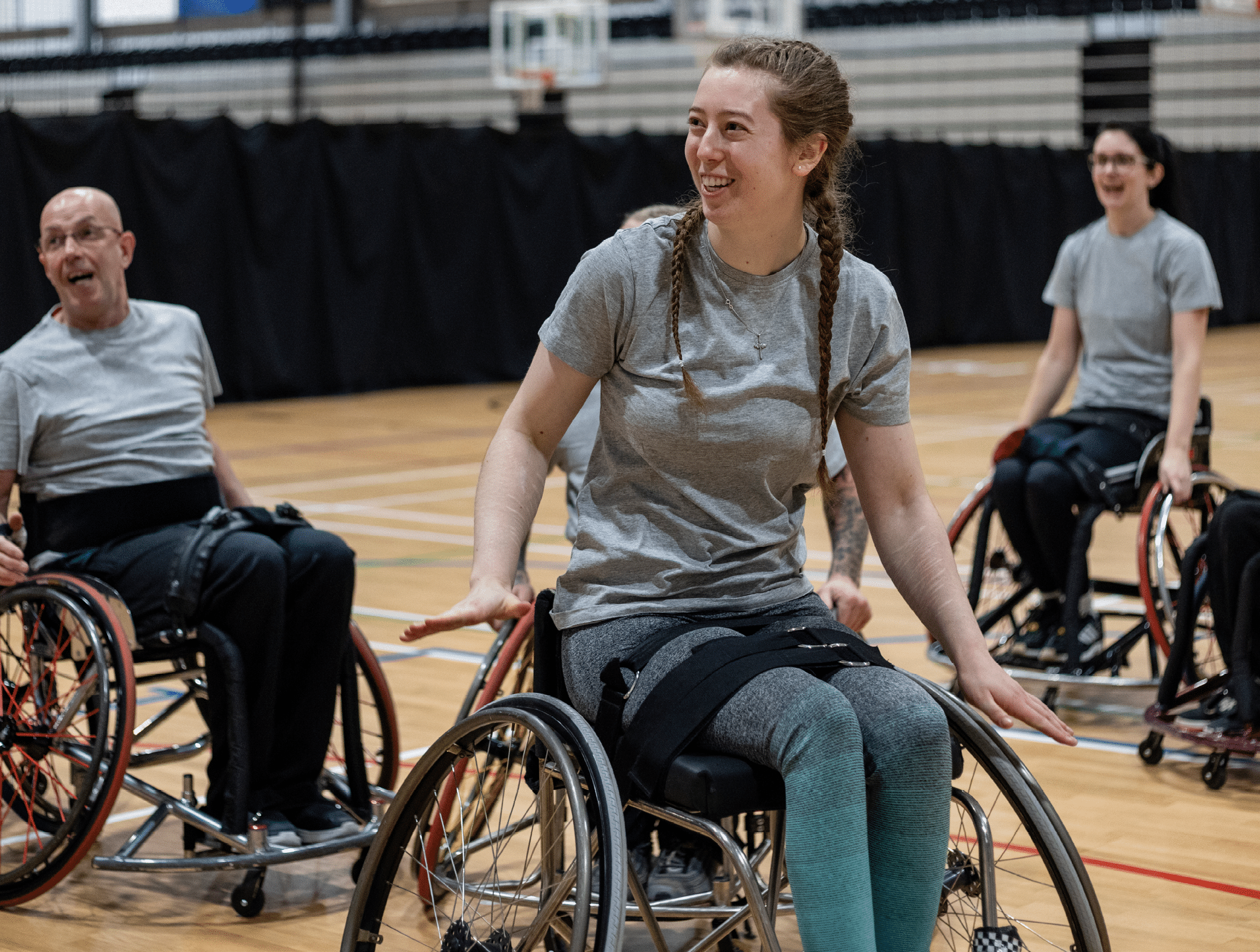 Wide shot of a team of wheelchair users playing basketball in the North East of England. They are competing against one another, laughing and having fun.
