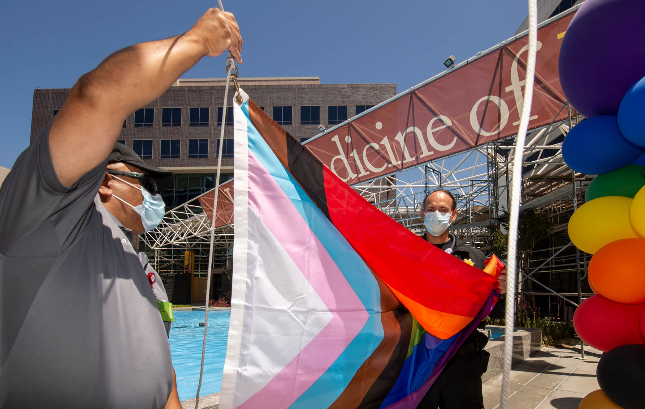 USC security officers Oscar Barajas, left and Gonzalo Zendejas, right, raise the Progress Pride Flag to kickoff Pride Month at Keck Medicine of USC, June 1, 2022  (Photo Gus Ruelas)  