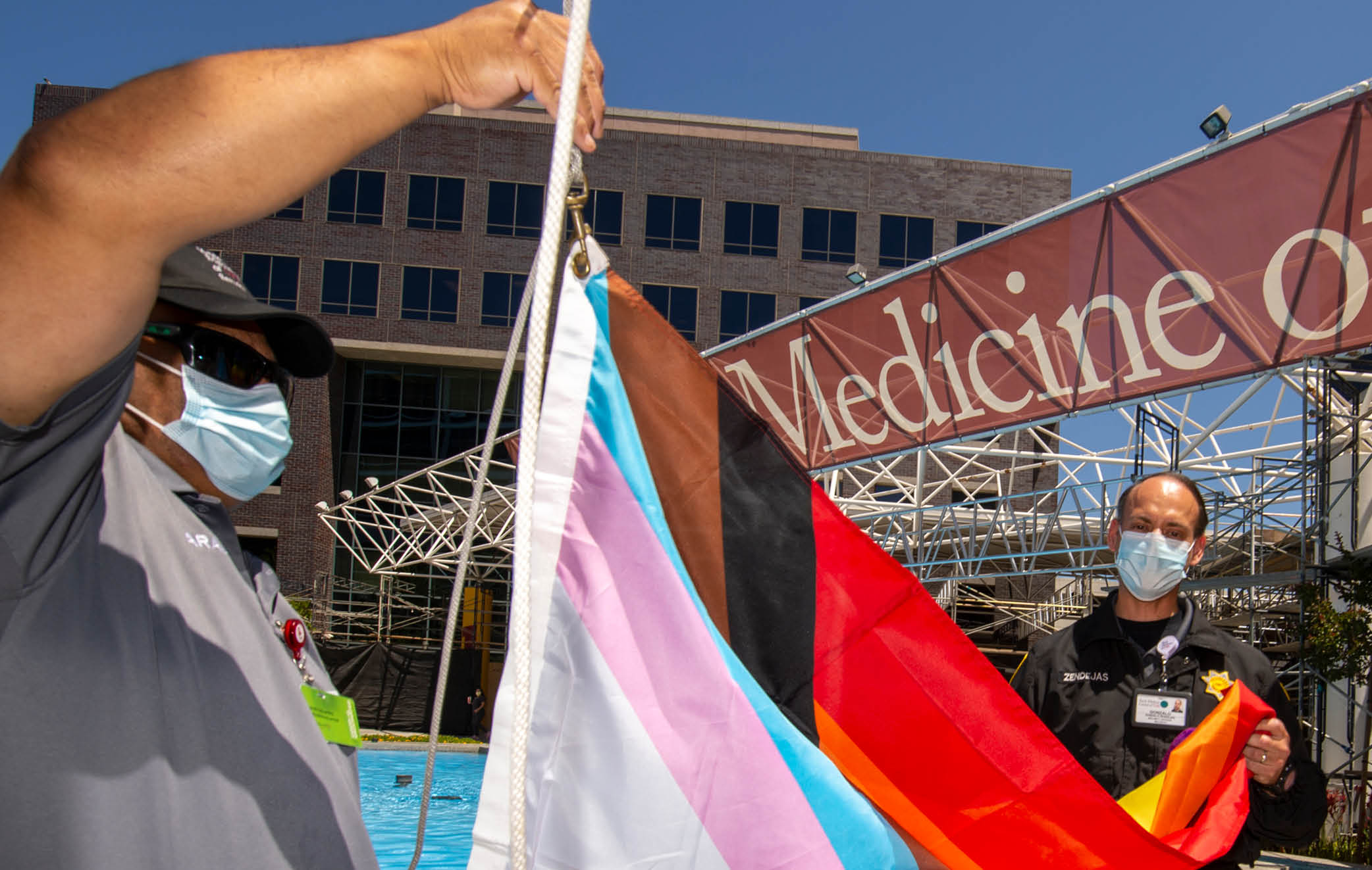 USC security officers Oscar Barajas, left and Gonzalo Zendejas, right, raise the Progress Pride Flag to kickoff Pride Month at Keck Medicine of USC, June 1, 2022  (Photo Gus Ruelas)  
